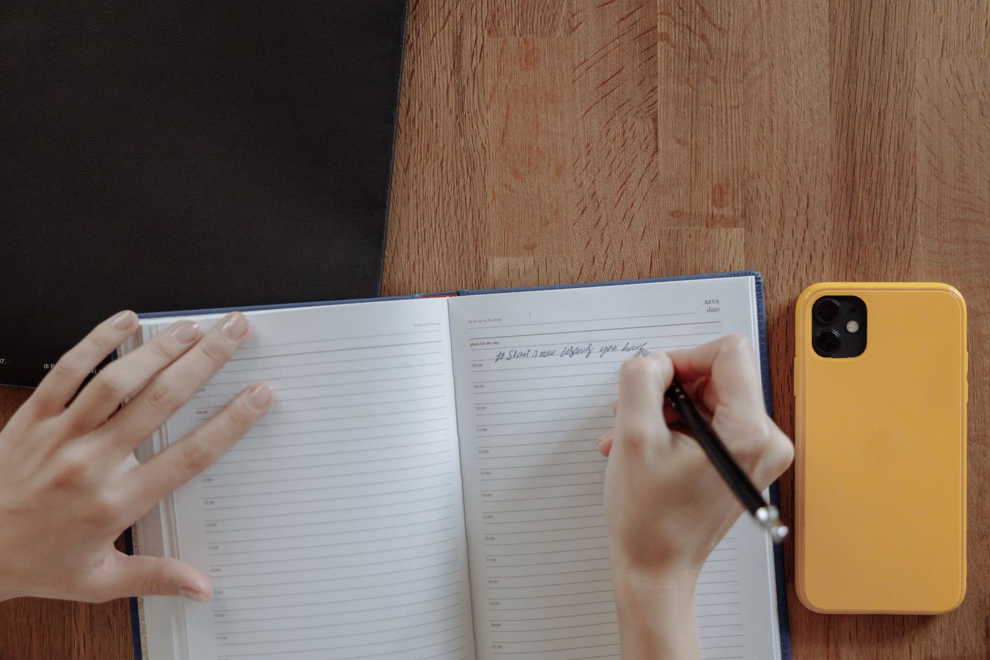 A person writing in an open notebook at a desk